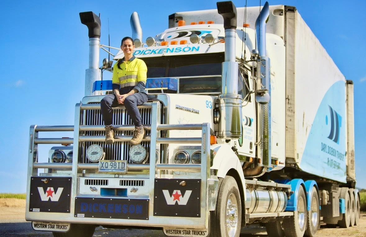 Female heavy vehicle driver seated on the bullbar of a Western Star truck